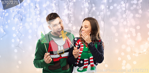 Image of couple with christmas party props in ugly sweaters