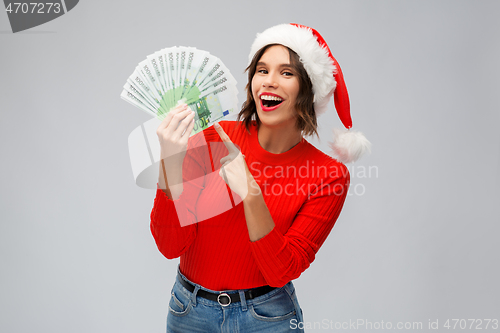 Image of happy woman in santa hat with money on christmas