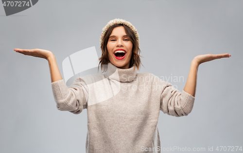 Image of young woman in winter hat holding something