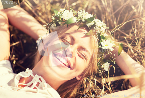 Image of happy woman in wreath of flowers lying on straw