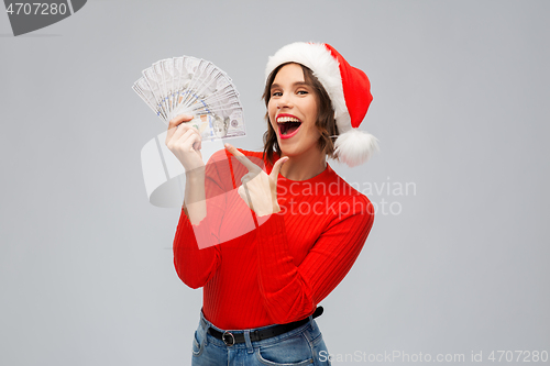 Image of happy woman in santa hat with money on christmas