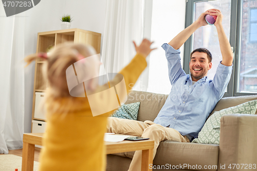 Image of father and baby daughter playing with ball at home