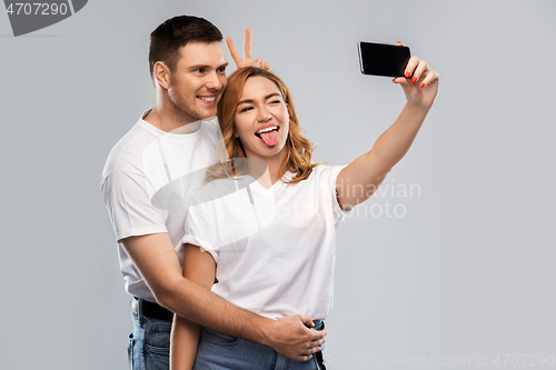 Image of happy couple in white t-shirts taking selfie