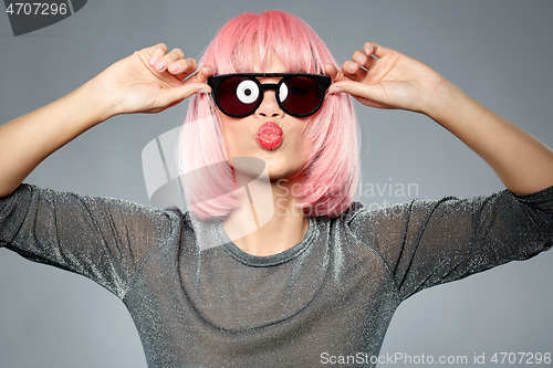 Image of woman in pink wig and sunglasses sending air kiss