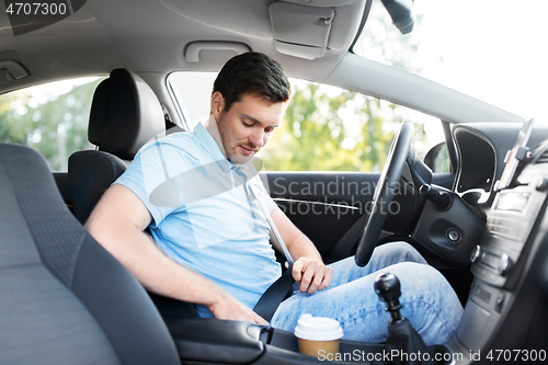 Image of man or car driver fastening seat belt