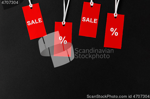 Image of red tags with discount signs on black background