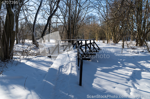 Image of Snowy trail with wooden footbridge 