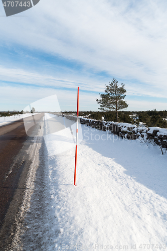 Image of Country road with a red snow stake by roadside