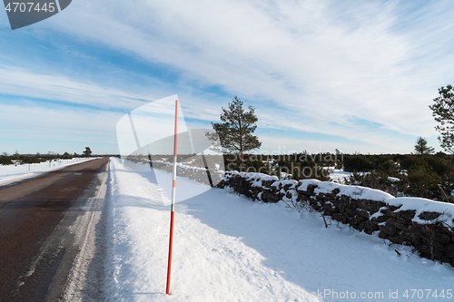 Image of Straight country road with a snow stake by roadside