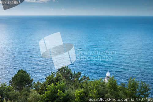 Image of Lighthouse behind the trees in cyan sea