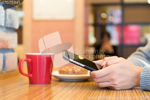 Image of Woman sending sms on mobile phone in cafe