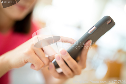 Image of Woman browsing mobile phone in cafe