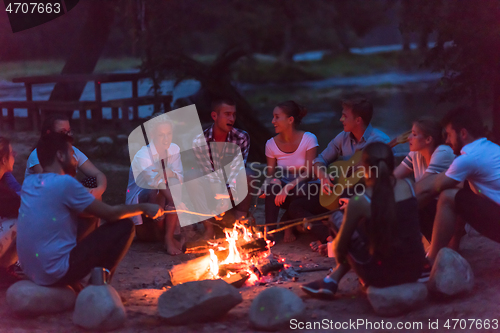 Image of young friends relaxing around campfire