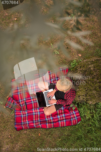 Image of top view of man using a laptop computer under the tree