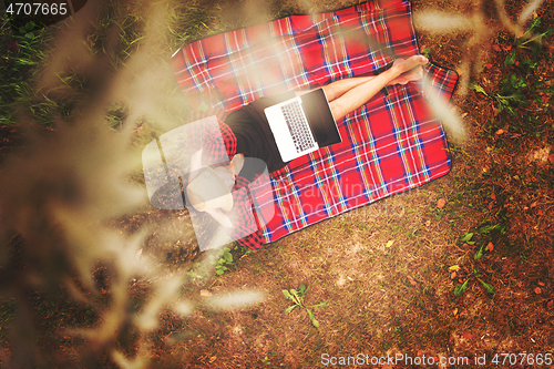 Image of top view of man using a laptop computer under the tree