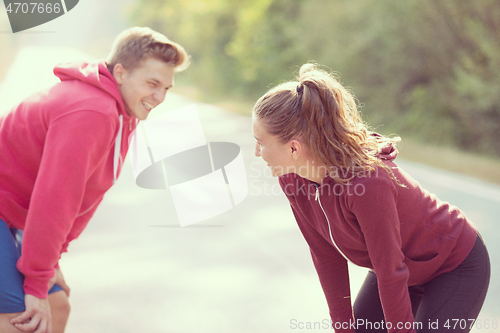 Image of young couple warming up and stretching on a country road