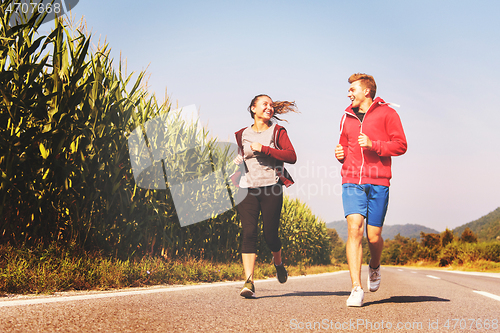 Image of young couple jogging along a country road