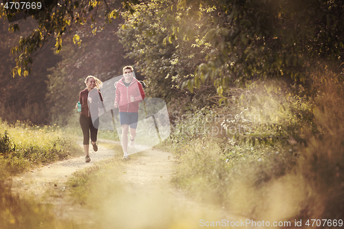 Image of young couple jogging along a country road