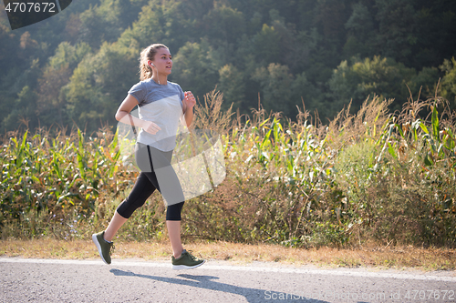 Image of woman jogging along a country road