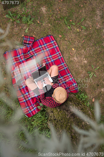 Image of top view of man using a laptop computer under the tree