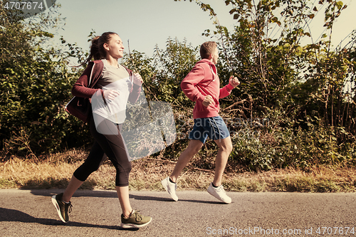 Image of young couple jogging along a country road