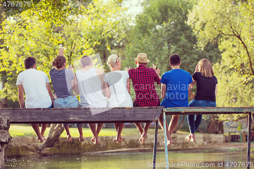 Image of rear view of friends enjoying watermelon while sitting on the wo