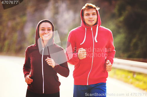 Image of young couple jogging along a country road