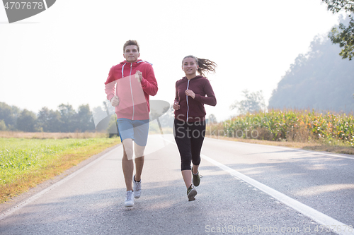Image of young couple jogging along a country road