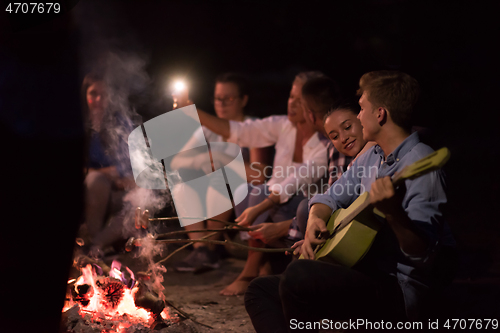 Image of young friends relaxing around campfire