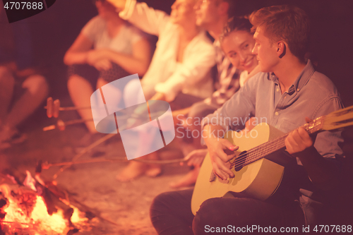 Image of young friends relaxing around campfire