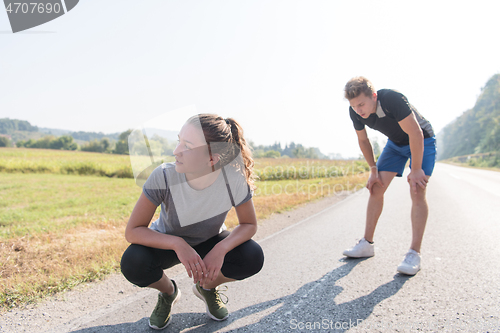 Image of young couple warming up and stretching on a country road