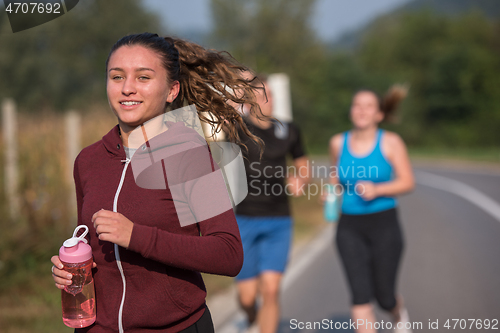 Image of young people jogging on country road