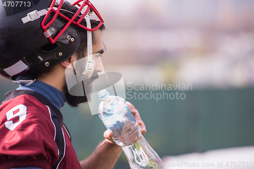 Image of american football player drinking water after hard training