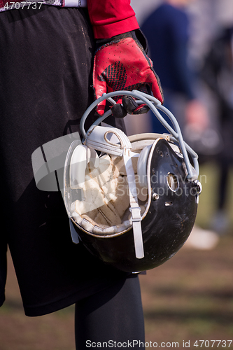 Image of American football player holding helmet