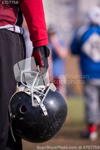 Image of American football player holding helmet