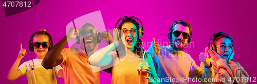 Image of Beautiful young people in neon light isolated on pink studio background