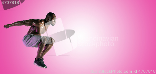 Image of Young african-american bodybuilder training over pink background