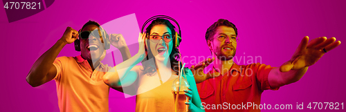 Image of Beautiful young people in neon light isolated on pink studio background