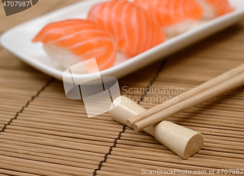 Image of chopsticks and sushi with salmon on the mat