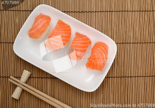 Image of chopsticks and sushi with salmon on the mat