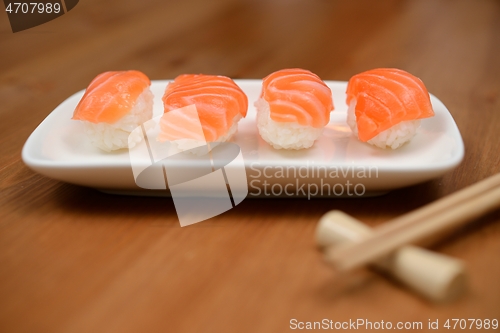 Image of chopsticks and sushi with salmon on the mat
