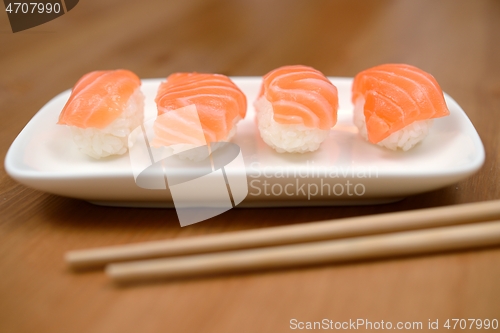 Image of chopsticks and sushi with salmon on the mat