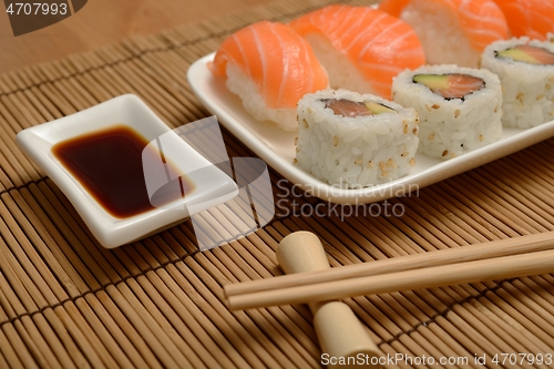 Image of chopsticks, soy sauce and sushi on the bamboo mat