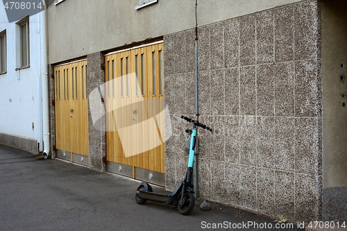 Image of an electric scooter is parked near the garage door of an buildin