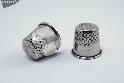 Image of two old metal tailor thimbles on a white