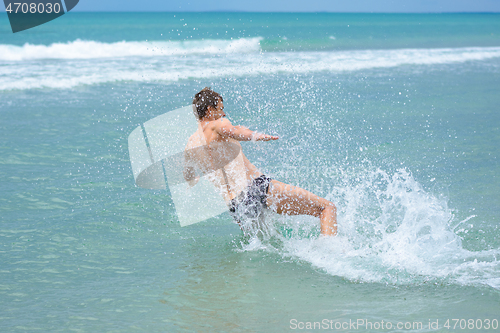 Image of A man accelerating from the shore jumps sideways into the sea water at the resort