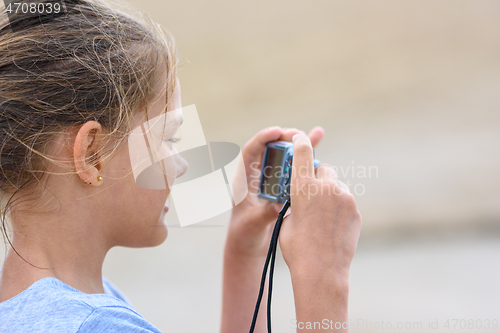 Image of Girl photographs moments from a beach holiday on a digital camera