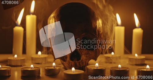 Image of Candles and human skull in darkness closeup footage