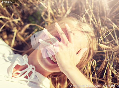 Image of happy young woman lying on cereal field