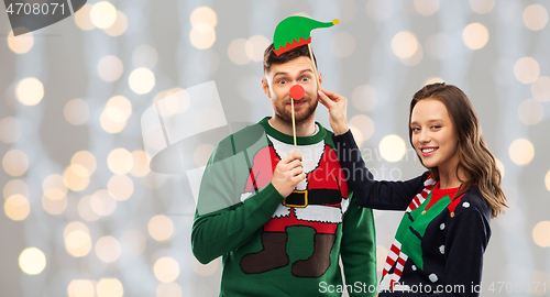 Image of couple with christmas party props in ugly sweaters